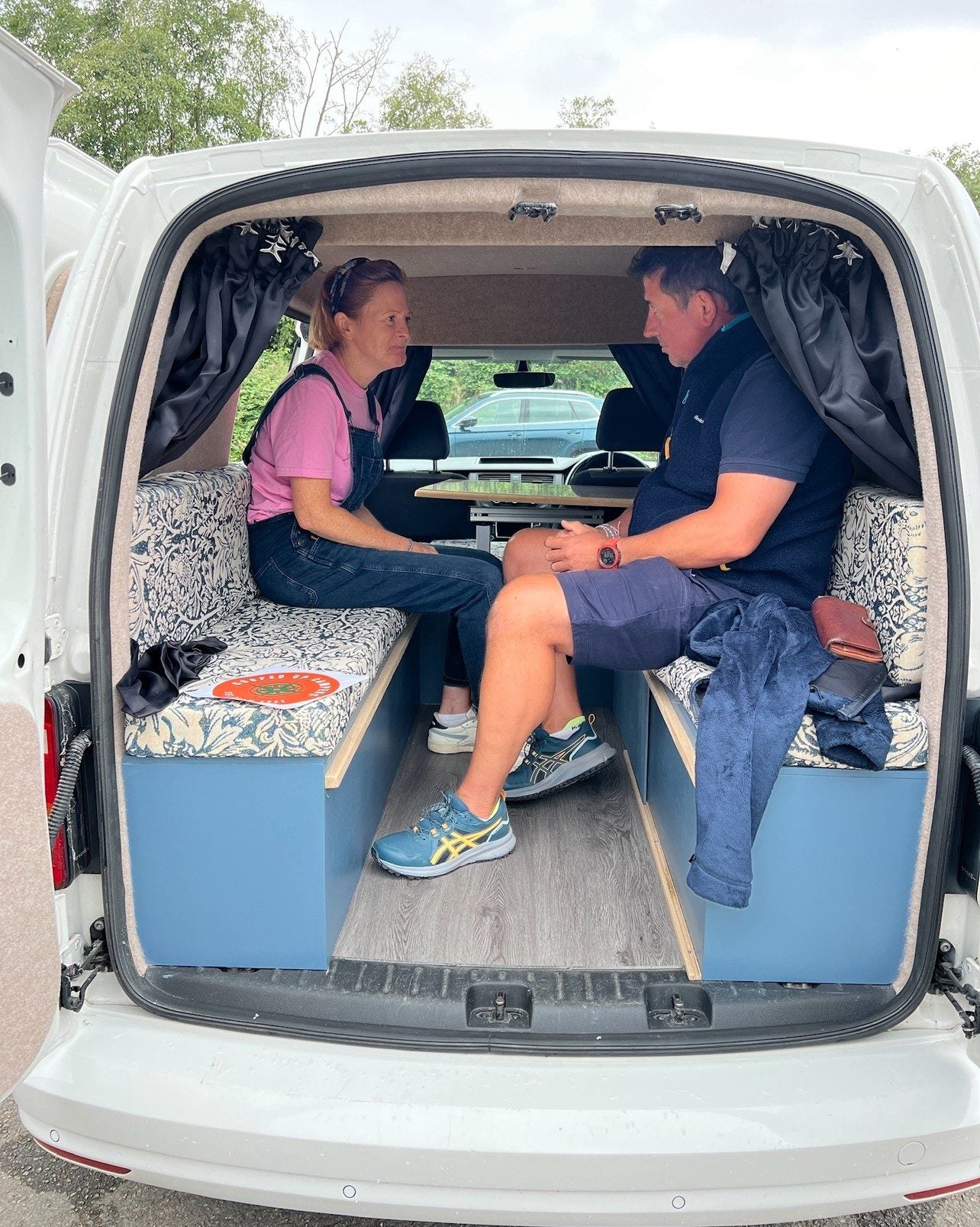 Two people sitting in the back of a finished Cooped Up Campers conversion